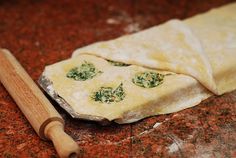 an uncooked pizza crust with spinach on it next to a rolling pin