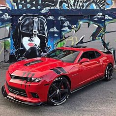 a red sports car parked in front of a graffiti covered wall