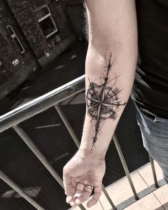 a person with a tattoo on their arm holding onto a handrail and looking down at the ground