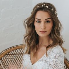 a woman sitting in a wicker chair wearing a white dress and flower headpiece