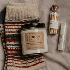 a pair of socks next to a jar of reading material on a bed with two candles