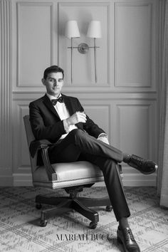 a man in a tuxedo sitting on a chair