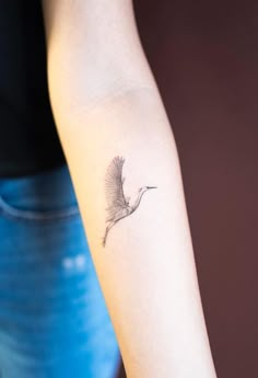 a woman's arm with a small bird tattoo on the left side of her arm