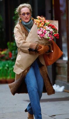 a woman walking down the street carrying flowers