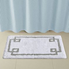 a white rug on the floor in front of a curtain with an ornamental border around it