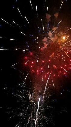 fireworks are lit up in the night sky with red, white and blue lights on them