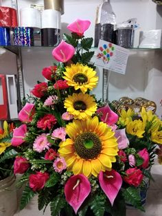 a vase filled with lots of colorful flowers on top of a table next to a shelf