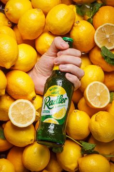 a person holding a bottle of beer surrounded by lemons