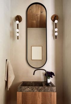 a bathroom sink sitting under a mirror next to a wall mounted faucet with lights on it