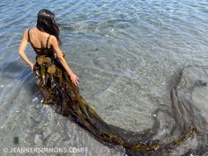 a woman is standing in the water with her long dress