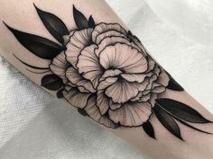 a black and white flower tattoo on the left arm, with leaves around it's edges