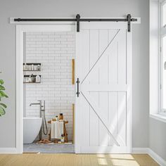 an open door leading to a bathroom with white walls and wood floors, along with a potted plant in the corner