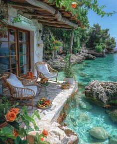 an outdoor area with chairs and tables next to the water in front of a house