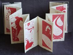 an open book with red and white designs on the pages, sitting on a black surface