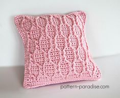 a pink crocheted pillow sitting on top of a white table