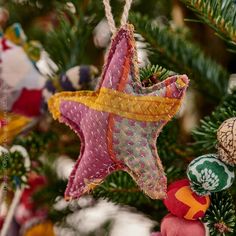 an ornament hanging from a christmas tree decorated with fabric stars and other ornaments