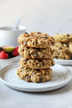 a stack of oatmeal cookies sitting on top of a white plate next to berries