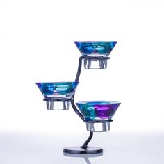 three glass bowls sitting on top of a metal stand in front of a white background