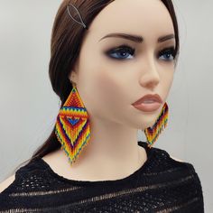 Stand out with these oversized beaded earrings, showcasing intricate tribal-inspired patterns in vivid yellow and orange tones. Handcrafted with meticulous attention to detail, these earrings blend warm, fiery shades to create a bold ethnic design. The vibrant color combination makes them perfect for adding a striking accent to any outfit, whether for casual wear or special occasions. These earrings are a true statement piece for those who love unique, eye-catching accessories. LENGTH WITHOUT HO Traditional Chandelier Earrings With Round Beads For Festivals, Traditional Yellow Earrings For Festival, Festival Large Beaded Earrings, Yellow Handwoven Earrings For Festival, Yellow Handwoven Festival Earrings, Traditional Beaded Chandelier Earrings For Festival, Traditional Chandelier Earrings With Colorful Beads For Festival, Traditional Multicolor Jewelry With Beaded Fringe, Festival Multicolor Beaded Fringe Chandelier Earrings