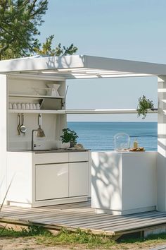 an outdoor kitchen with the ocean in the background and trees to the side, on a wooden deck