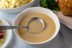 a bowl of soup with a spoon in it next to some other dishes on a table