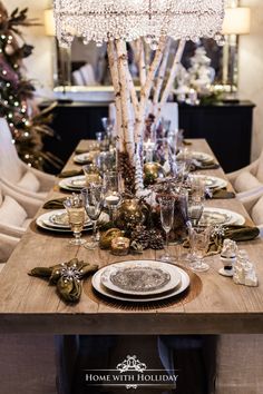 a dining room table is set for christmas with silver and gold decorations on the tables