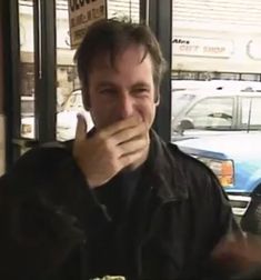 a man sitting at a table in front of a plate of food with his finger up to his mouth