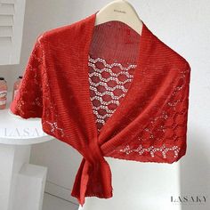 a red shawl draped over a mannequin's torso in front of a white wall