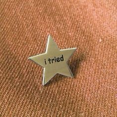 a pin with the word i tried on it sitting on top of a brown cloth