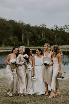 a group of women standing next to each other in front of a body of water