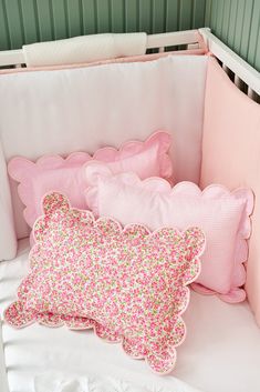 pink and green pillows in a white crib