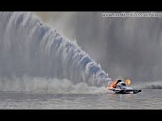 a person on a jet ski in front of a large wave with water sprays behind them