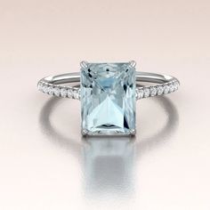 an aqua blue topazte ring with diamonds on the band and side stones in white gold