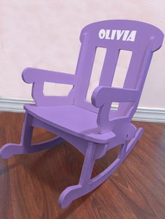 a purple rocking chair sitting on top of a hard wood floor