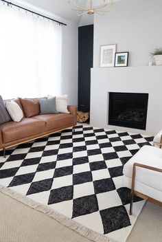 a black and white checkered rug in a living room with two couches, a fireplace and a chandelier