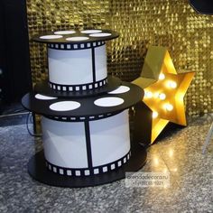 a movie themed cake with lights on it and a star next to it in front of a gold wall