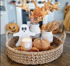 a basket filled with candles and decorations on top of a wooden table next to pumpkins