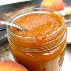 an apple jam in a glass jar with a spoon