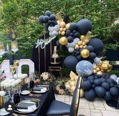 a table set up with black and gold balloons