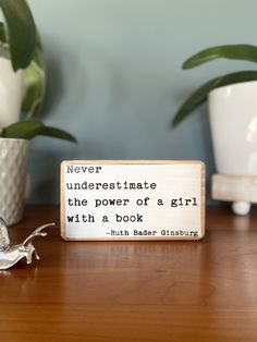 a wooden block that says never underestimate the power of a girl with a book