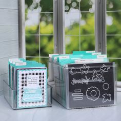 two clear boxes sitting next to each other on top of a white counter with windows in the background