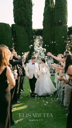 a bride and groom walk down the aisle as confetti is thrown in the air