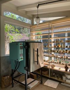 a room filled with lots of shelves next to a window covered in glass coverings