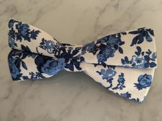 Upgrade your wardrobe in style with this stunning white and blue floral cotton bow tie. Perfect gift for him, this unique adjustable bow tie will elevate any occasion including weddings, birthdays and anniversaries. Comes pre-tied. White Bow Tie For Spring, White Bow With Tie Back For Spring, Classic White Bow For Summer, Elegant White Bow Tie For Spring, Classic White Bow Tie For Spring, White Dapper Bow Tie For Summer, White Satin Bow Tie For Spring, Embroidered Bow, Blue Floral Pattern