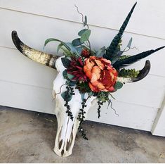 an animal skull with flowers on it's head sitting in front of a garage door