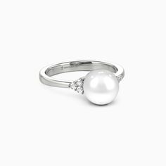 Celebrate everlasting love with this exquisite side-stone ring. A captivating pearl center stone radiates elegance, while trios of round gems on each side create an enchanting constellation of light. Additionally, this ring is crafted from highly polished precious metal, offering an irresistible luster and a comfortable fit. It is a symbol of love's timeless glow, designed to be cherished forever. *Each piece is handmade, resulting in a potential variance of 0.1-0.2mm during measurement. Please Anniversary Pearl Ring With Three Stones, Three Stone Pearl Ring For Anniversary, White Gold Pearl Ring With Center Stone, White Gold Pearl Rings With Round Cut, Elegant Three Stone Pearl Ring For Anniversary, Elegant Pearl Ring With Round Cut, Elegant Round Cut Pearl Ring With Gemstone, Elegant Round Cut Pearl Ring, Pearl Rings With Brilliant Cut For Anniversary