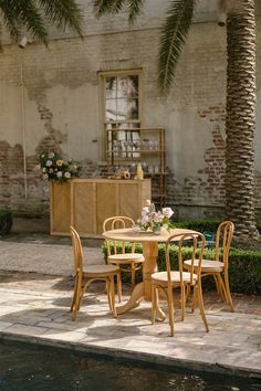 a wooden table with four chairs next to a pool