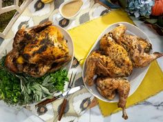 two plates with roasted chicken and vegetables on a yellow table cloth next to a potted plant