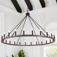 a chandelier hanging from the ceiling in a room with white walls and wooden beams