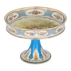 an ornate blue and white bowl with flowers on the bottom, sitting on a pedestal